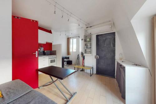 een keuken met een tafel en een rode muur bij 2 pièces Lumineux & Calme (28m²) in Parijs