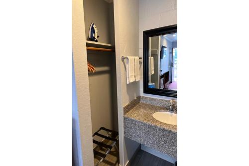 een badkamer met een wastafel en een spiegel bij The Islander Motel Santa Cruz in Santa Cruz