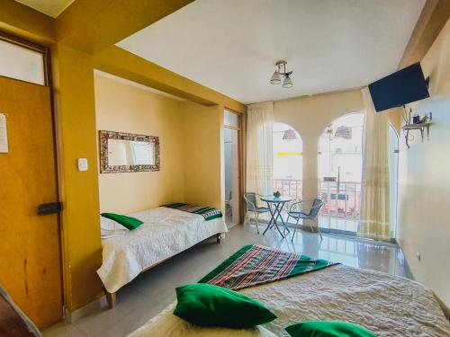 Un dormitorio con 2 camas y una mesa con balcón. en Hostal Mendieta, en Paracas