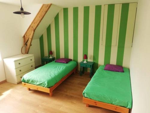 two beds in a room with green and white stripes at Le tie-break in Pont-Croix