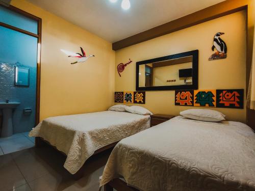 a bedroom with two beds and a mirror at Hostal Mendieta in Paracas