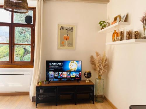 un salon avec une télévision à écran plat sur une table dans l'établissement Maison Gabriel - Logement charmant au cœur de la Cité Médiévale - T3 75m2, à Albertville