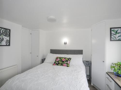 een witte slaapkamer met een wit bed en een kussen bij Rhiwlas Bach in Benllech