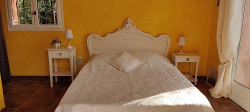 1 dormitorio con 1 cama blanca y 2 mesitas de noche en Sous les oliviers, en Tourrettes