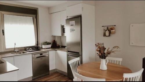 a kitchen with a wooden table and a refrigerator at O Saramagal-Casa Nueva playa Area Brava - HIO in Hio