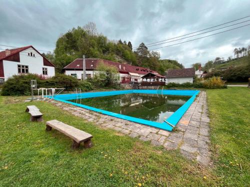 a swimming pool with two benches in a yard at U Cvečků 