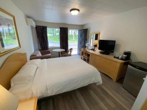 Habitación de hotel con cama y TV en Motel Panoramique en Saguenay