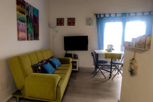 ein Wohnzimmer mit einem gelben Sofa und einem Tisch in der Unterkunft Attico panoramico in Fiumicino