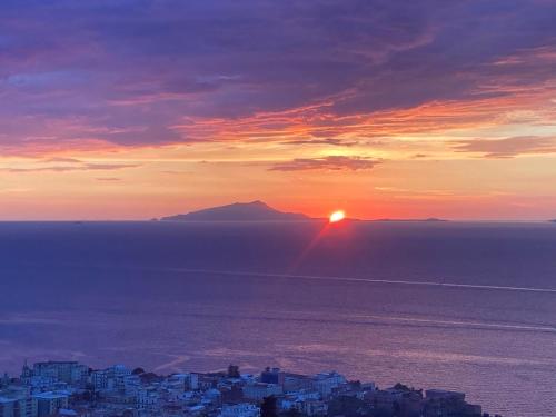 a sunset over the ocean with a mountain in the background at Maison Danielle in Vico Equense