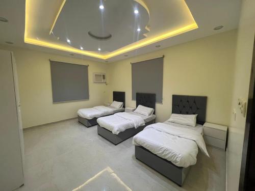 een kamer met drie bedden en een projectiescherm bij شقة كبيرة 3 غرف نوم وصالة Large apartment with 3 bedrooms and a living room in Taif