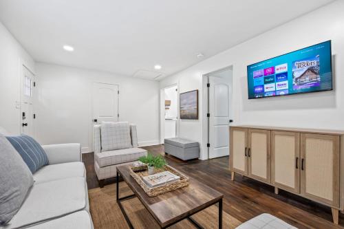 a living room with a couch and a tv on a wall at Charming Saints Street Cottage in Lafayette
