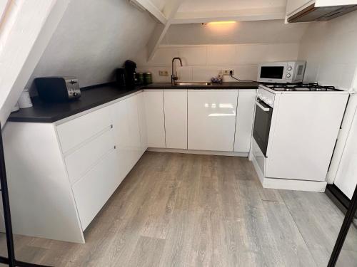 a kitchen with white cabinets and a stove top oven at Church Square Studio in Zandvoort