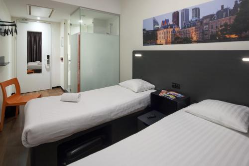 a hotel room with two beds and a mirror at easyHotel The Hague City Centre in The Hague