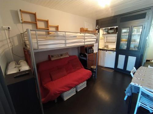 a bedroom with a bunk bed and a red couch at Studio 3 personnes au pied des piste plateau de Bonascre - Ax 3 domaines Eté Hiver in Ax-les-Thermes