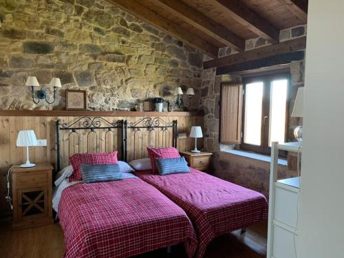 a bedroom with two beds and a stone wall at El manantial in Liérganes