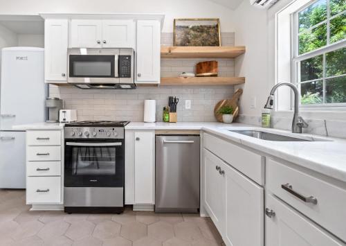 a kitchen with white cabinets and a stove and microwave at Saints Street Charmer in Lafayette
