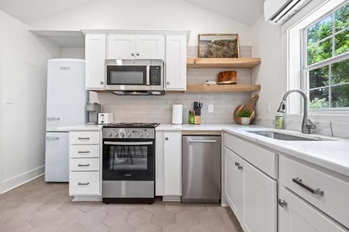 uma cozinha com armários brancos, um fogão e micro-ondas em Saints Street Cottage em Lafayette
