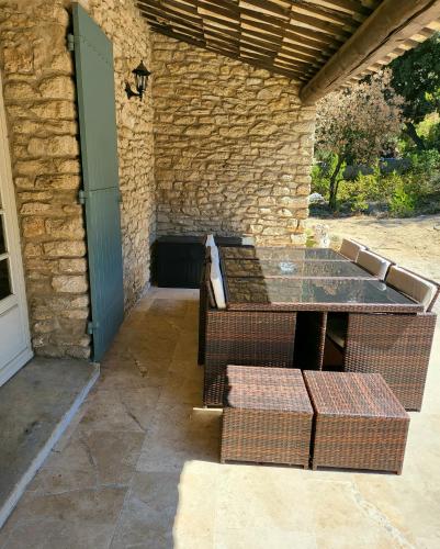 un patio avec une table et des chaises et un mur en pierre dans l'établissement maison au cœur de la colline, à Cavaillon