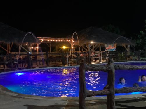 una piscina por la noche con gente en ella en Hotel la Isla campestre, en Villavieja