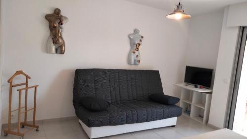 Una sala de estar con un sofá y un televisor. en Studio avec terrasse 2 personnes, en Le Lavandou