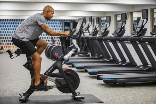 a man riding a exercise bike in a gym at voco Fiorello - LaGuardia East by IHG in Queens