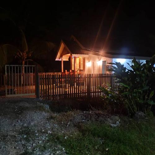 a house with a fence in front of it at night at Kampung Cottage Bagan Datuk in Selekoh