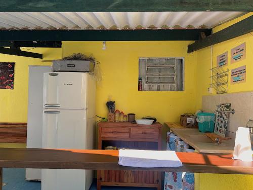 a kitchen with a white refrigerator and a yellow wall at Hostel Coraticum in Ubatuba