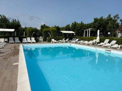 a large blue swimming pool with lounge chairs and umbrellas at Hotel Park in Rossano