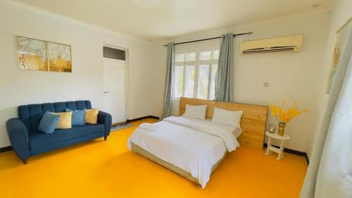 a bedroom with a bed and a blue couch at Gallivanters Hostel in Dar es Salaam