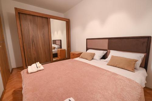 a bedroom with a large bed with a large mirror at Apartman Oskar in Podgorica