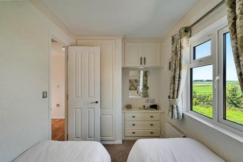 a white bedroom with two beds and a window at Finest Retreats - Seacroft in Torpoint