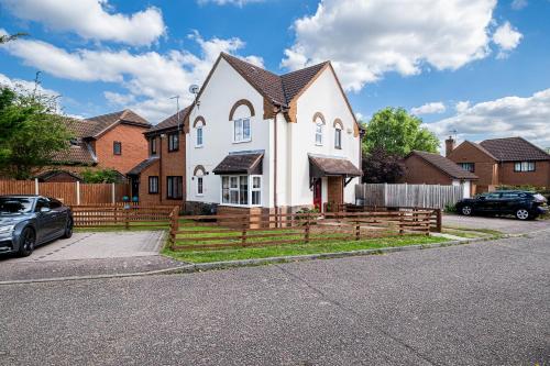 a white house with a fence in front of it at Wheatley House in Milton Keynes