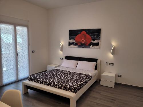 um quarto com uma cama com uma flor vermelha na parede em SP Rooms em Isola delle Femmine