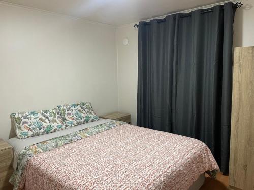 1 dormitorio con cama y cortina azul en Casa entera para 2 o 4 personas, en Temuco