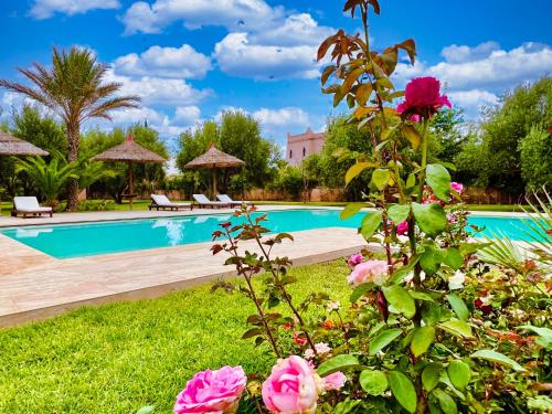 a pool with pink roses in a garden at Villa Riadi in Marrakech in Marrakesh