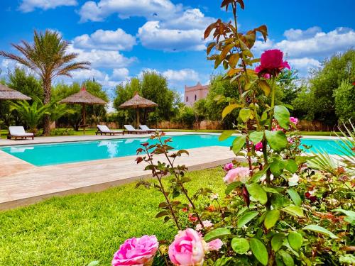 a pool with pink roses in a garden at Villa Riadi in Marrakech in Marrakech