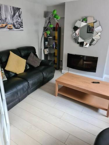a living room with a black leather couch and a coffee table at MASSIVE 4 Bed home walking distance to the City lights, perfect for business trips in Belfast
