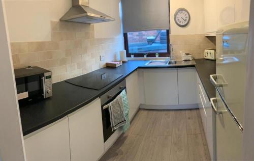 a kitchen with white cabinets and a black counter top at Shotley Bridge - Large Stylish 3 Bedroom Apartment in Consett
