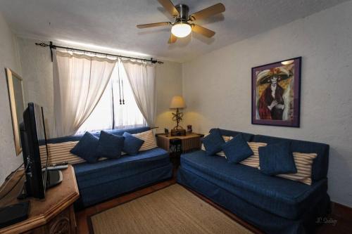 a living room with two blue couches and a television at Home in San Miguel de Allende. Casita de La Aldea in San Miguel de Allende