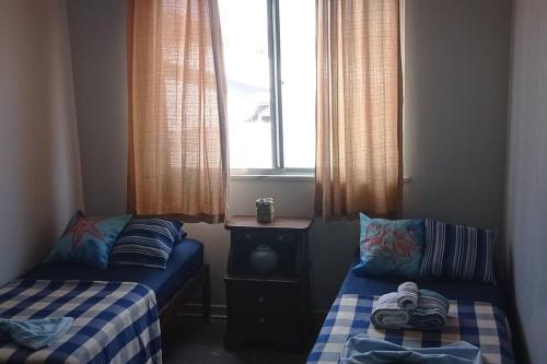 2 camas en una habitación pequeña con ventana en Casa em Condomínio tranquilo bem perto da praia! en Saquarema
