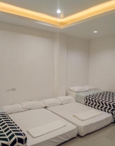 two beds in a room with white walls at Majestique Hotel Albay Bicol in Guinobatan