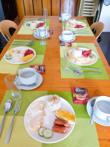 a wooden table with plates of food on it at Majestique Hotel Albay Bicol in Guinobatan