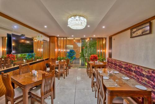 a restaurant with wooden tables and chairs and a chandelier at Height View Residency in Dehradun