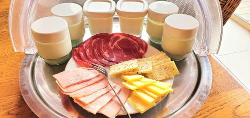 a plate of food with cheese and meats and drinks at "La Coustille" Chambres et Table d'Hôtes in Saint-Léger-les-Mélèzes