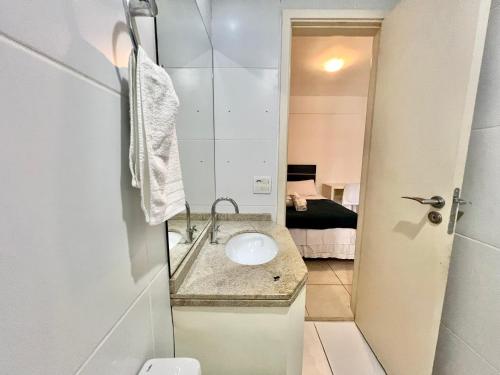 W łazience znajduje się umywalka z lustrem i toaleta. w obiekcie Apt em condominio beira-mar completo, piscina, WIFI 350Mbps, Ar condicionado, cama e sofá perfeitos w mieście Maceió