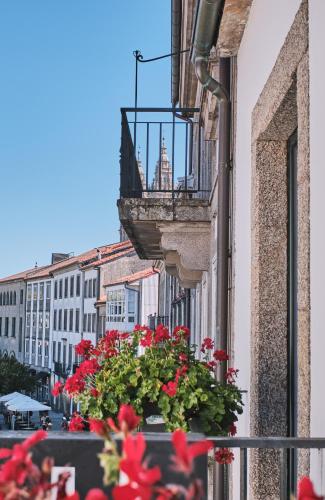 a balcony with red flowers on a building at Hotel Entrecercas in Santiago de Compostela