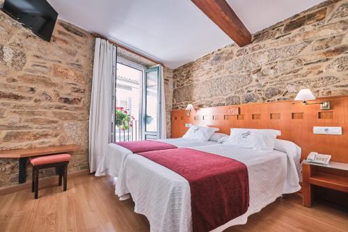 sypialnia z dużym łóżkiem i kamienną ścianą w obiekcie Hotel Entrecercas w Santiago de Compostela