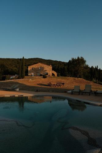 uma piscina de água com dois bancos e um edifício em VIN Hotel - Wine Resort and Agriturismo Montieri em Montieri