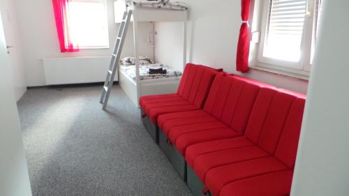 a red couch in a room with a ladder at Hostel Levicki in Slavonski Brod