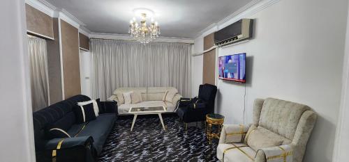 een woonkamer met een bank en stoelen en een tv bij Unique Apartment in Sheraton Heliopolis in Caïro